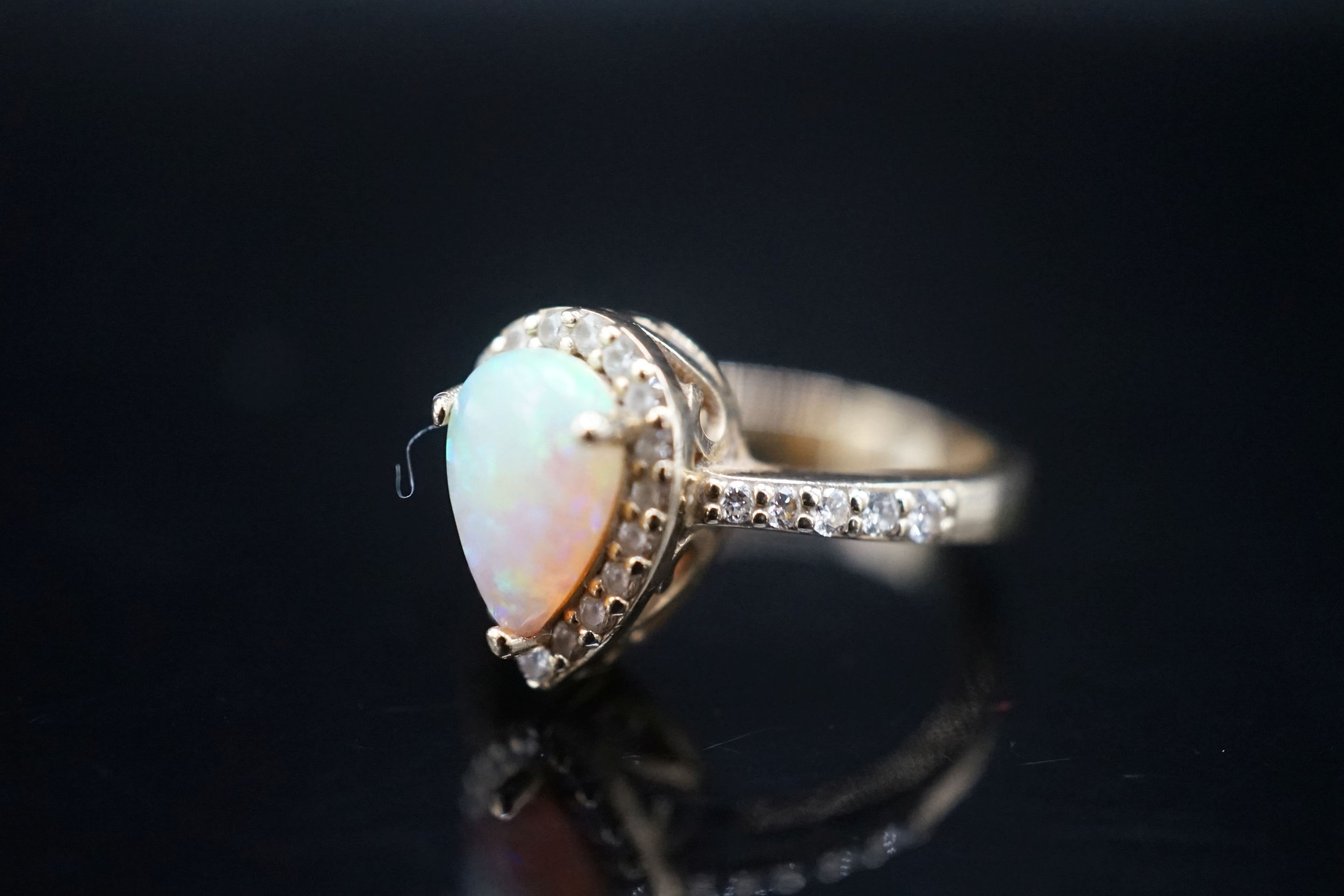 A modern 14k yellow meta, white opal and diamond set pear shape cluster ring, with diamond set shoulders, size K, gross weight 4.3 grams.